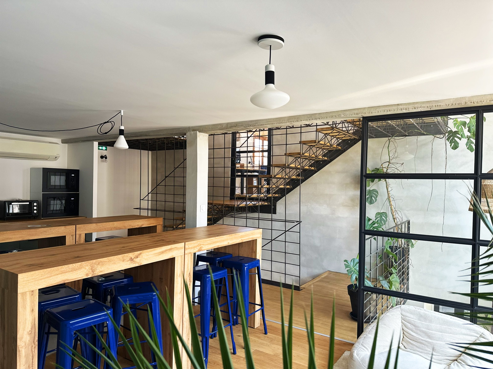 La cuisine commune des bureaux Multani, grande table haute en bois et tabourets bleus